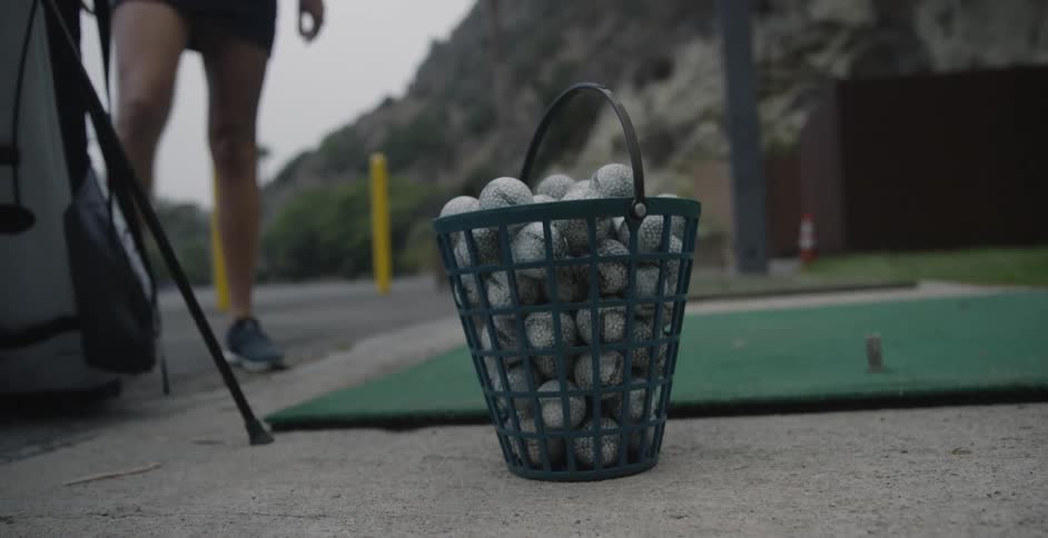 A woman golfs at a driving range