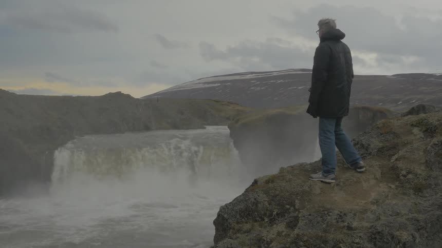 A man is watching a waterfall