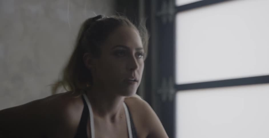 A woman is working out on a stationary bike in a gym during the day
