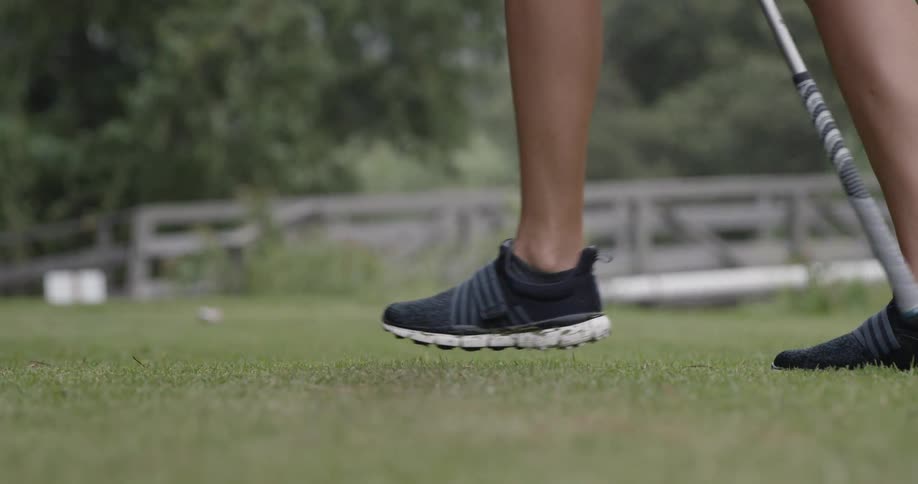 Someone is wearing golf shoes and carrying a golf club