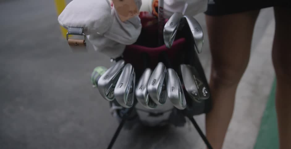 A woman looks at clubs in a golf bag