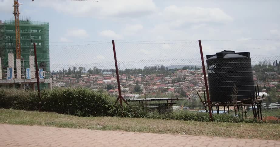 Passing view of a city area with people walking and a building under construction on a cloudy day