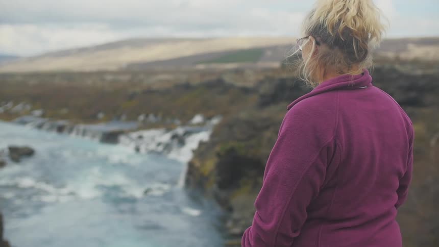 Woman standing on a hill overlooking a river