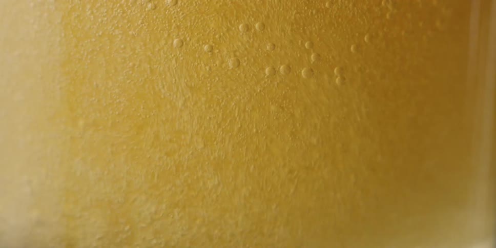 A beverage is poured into a glass and causes foam