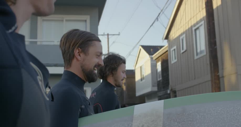 Men wear wetsuits while walking with surfboards