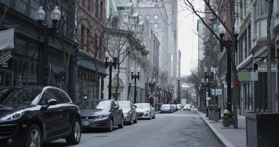 A car is driving down an urban one way street during the day