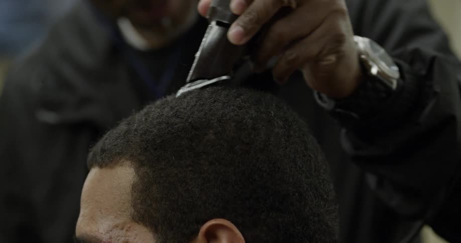 A man trims another's man hair with an electric clipper