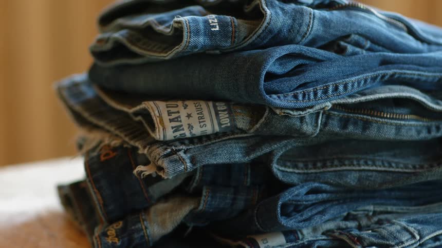 Jeans sit folded in a pile
