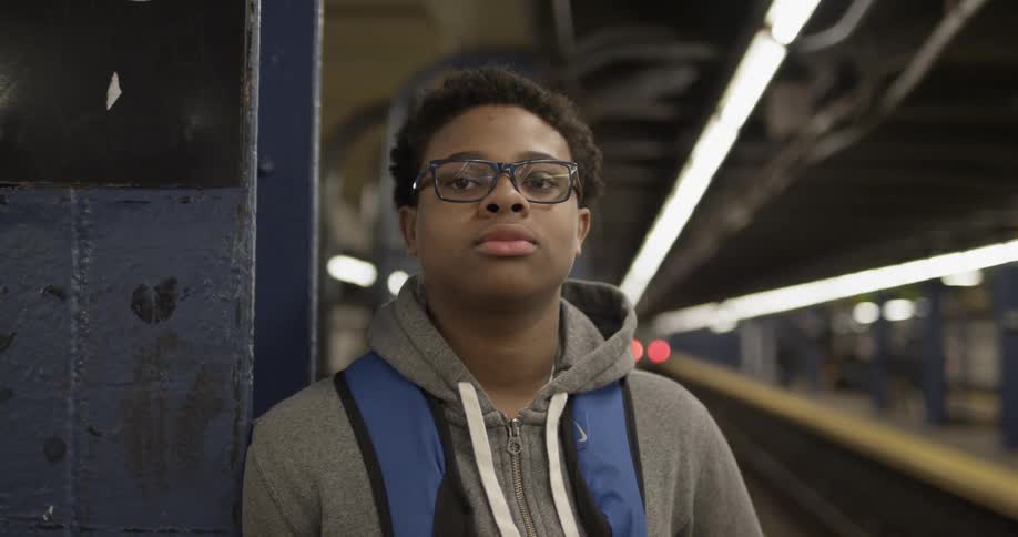 A man leans against a steel post in a subway station