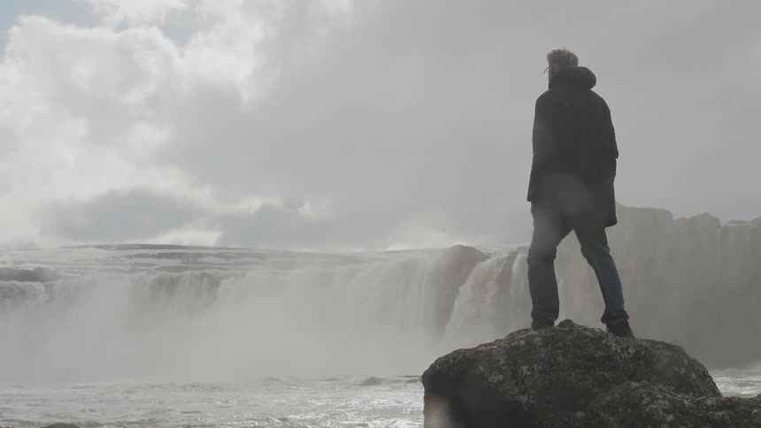 A man is watching a waterfall