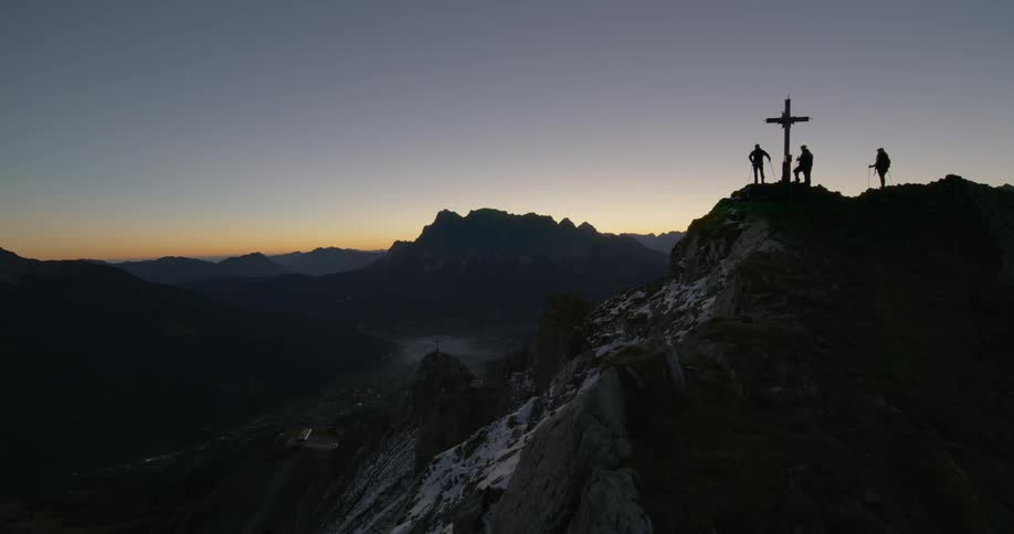 Climbers stand on a peak where a cross has been raised