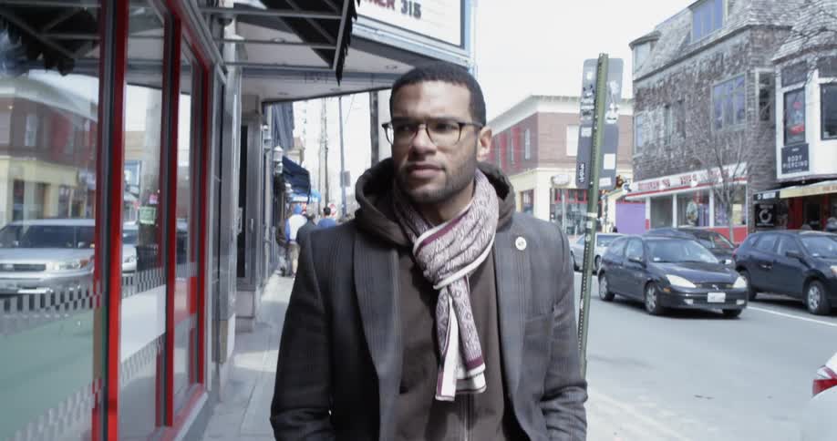 A man is walking down the sidewalk looking around