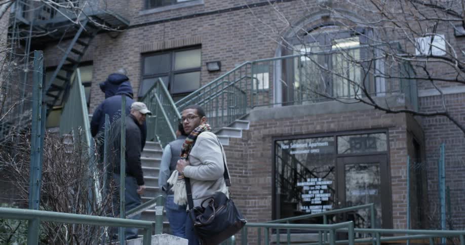 A group of people are walking up some steps to a brownstone building