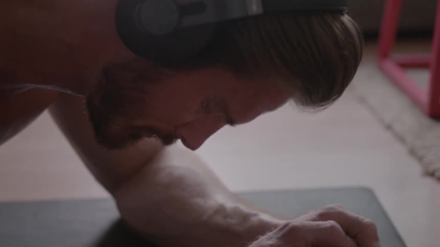 A man wearing headphones sweats as he stretches