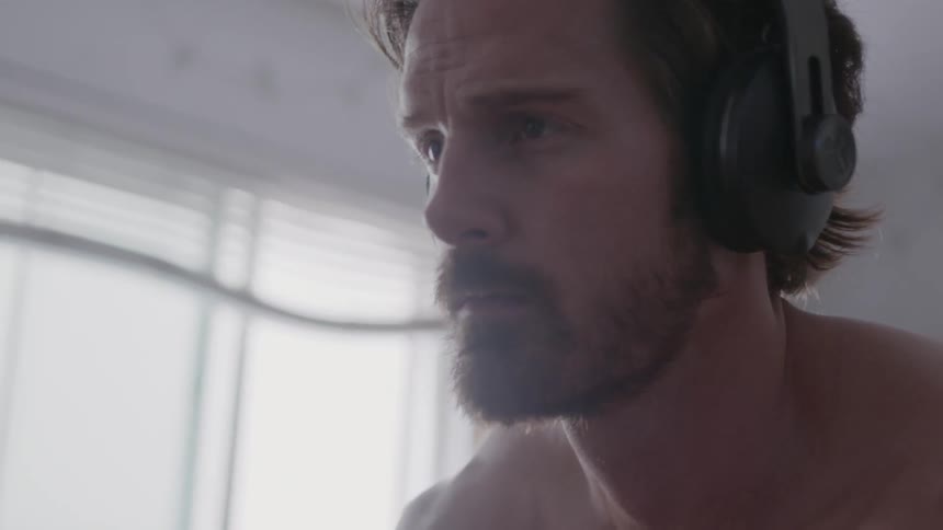 A man looks up while listening to headphones
