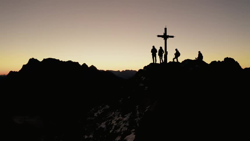 Skiers stand on a peak where a cross has been raised
