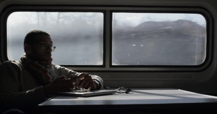 A man is sitting on a train looking at his phone