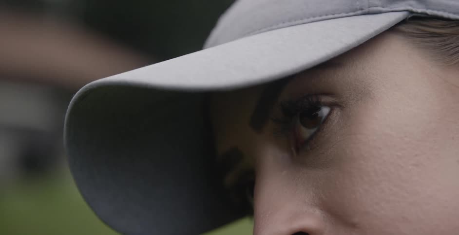 A female golfer is turning her head as she prepares to take a swing
