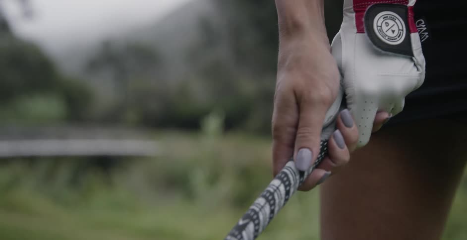 A woman is gripping a golf club about to swing