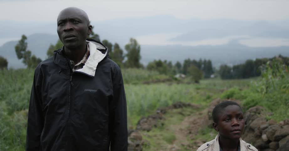 A man and boy stand on the green field
