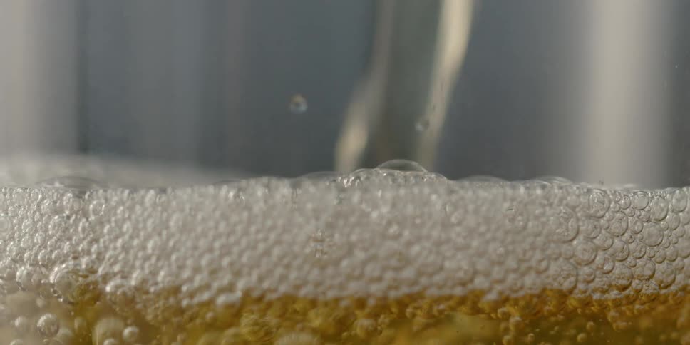 Water flows into a glass creating bubbles