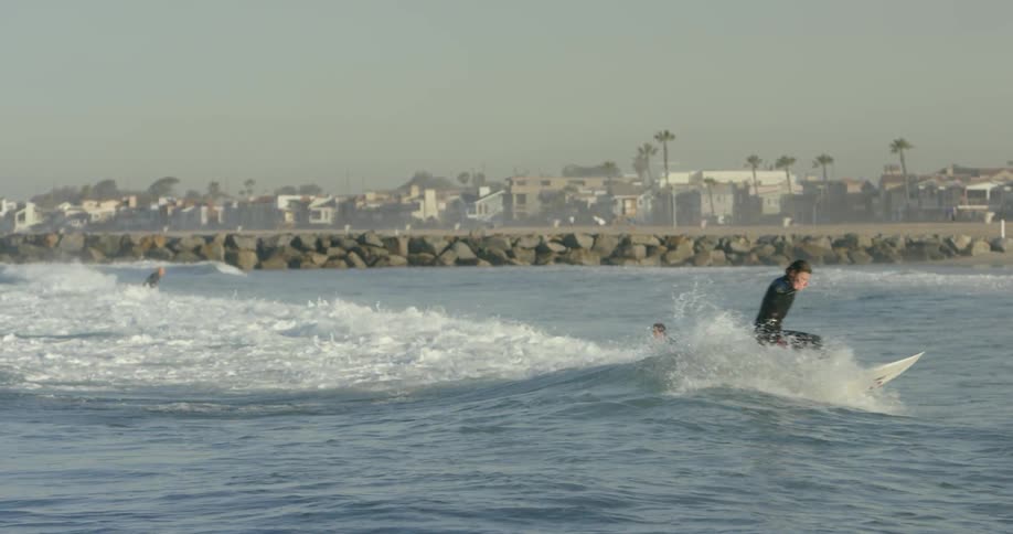 Surfer riding a small wave before a rock wall