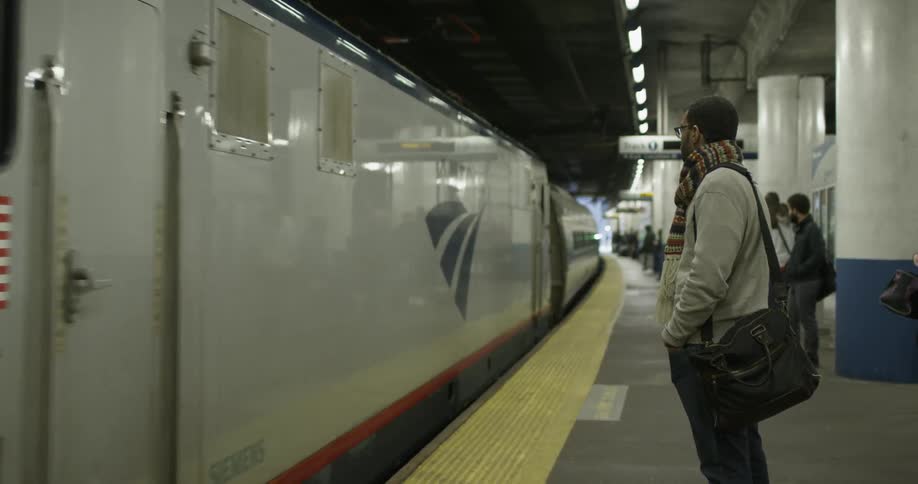 A man stands on the platform as an amtrak train pulls in
