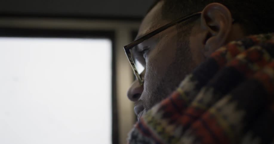 A man wears a scarf while riding on a train