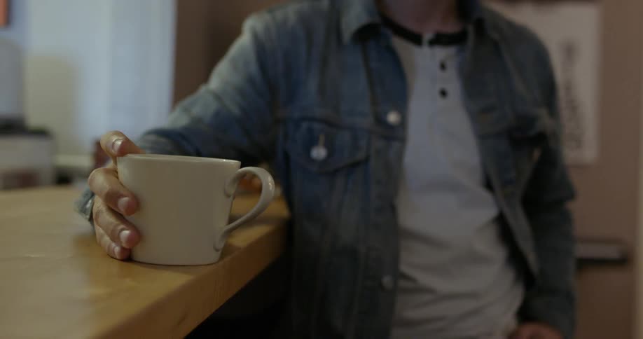 A person sits at the table holding a mug