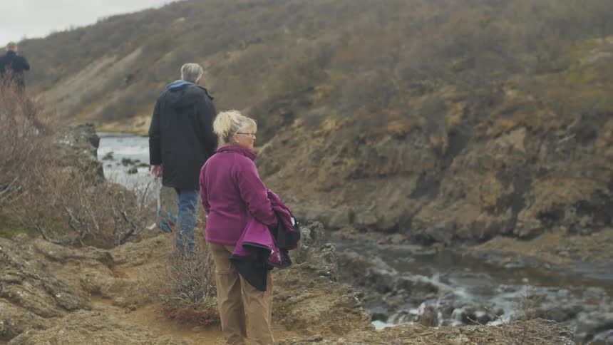 People walking along a cliff with rapids below