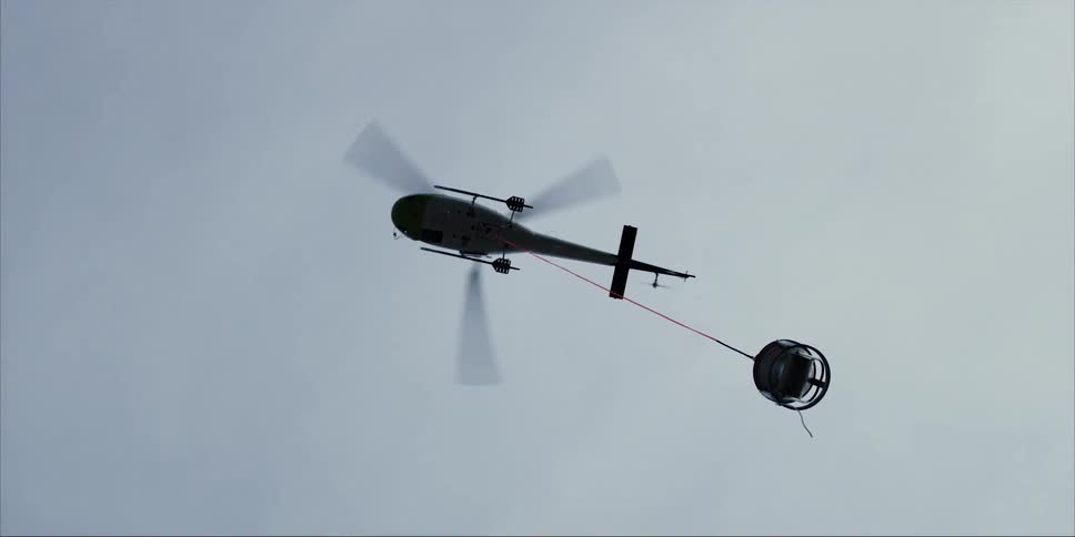 The helicopter is carrying a container as it flies in the sky