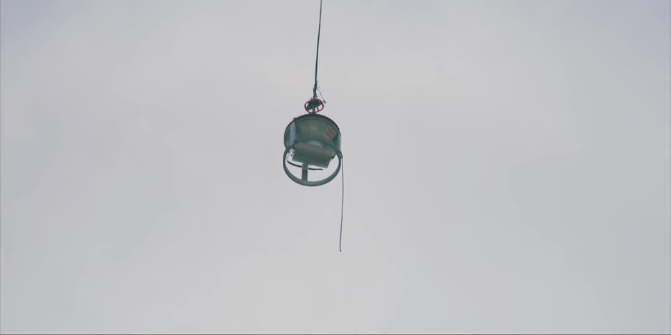 Metal bin in the sky being pulled up by a rope