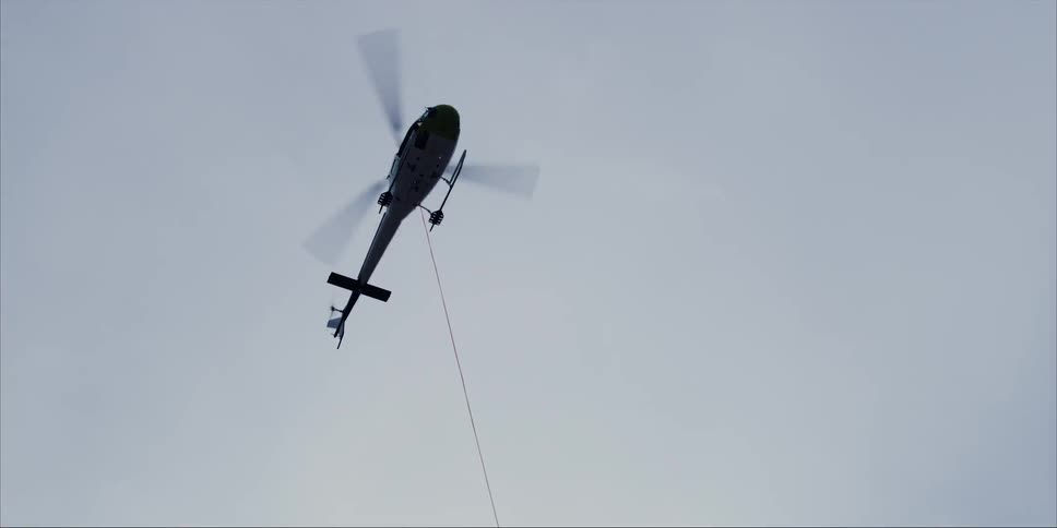 Helicopter hovers in the air with a long rope hanging from it