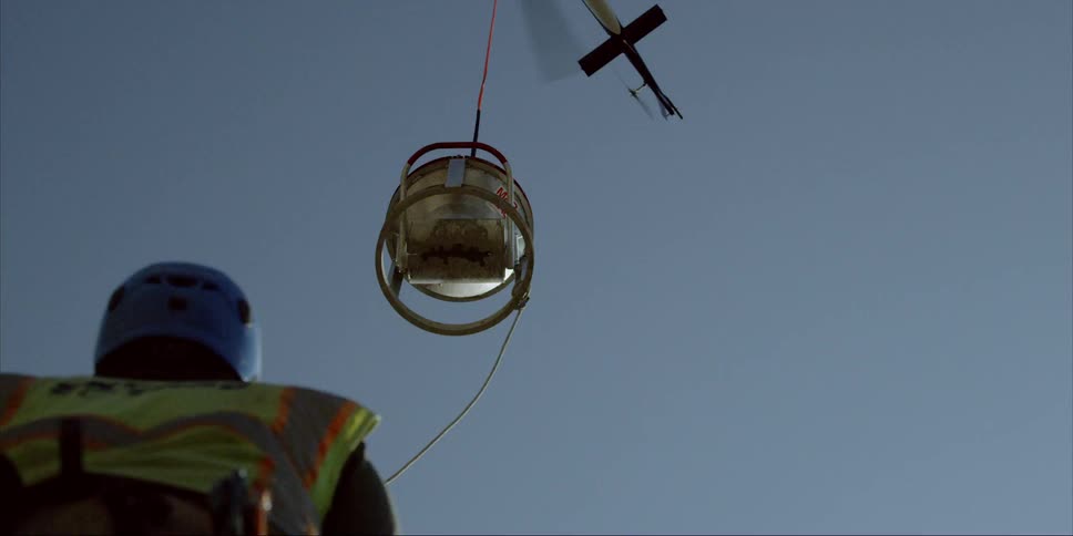 A helicopter is dangling a canister over a person