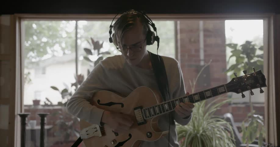 A man plays guitar in a music studio