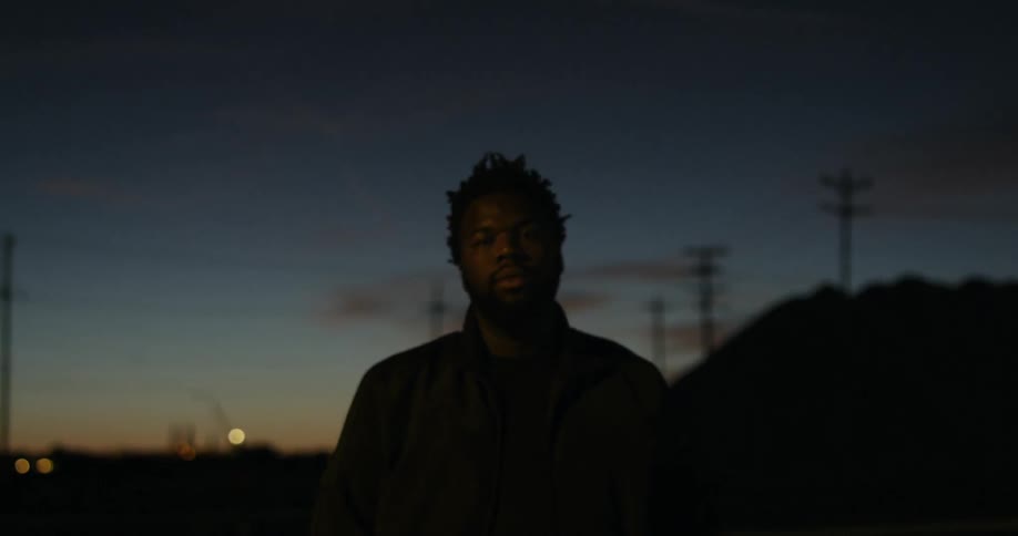 A man is standing in the street at sunset