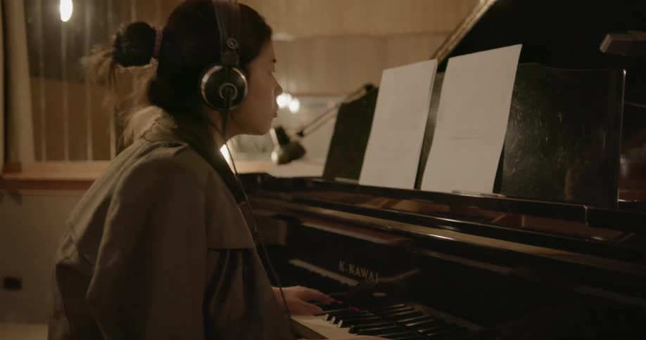 A musician plays piano in a recording studio