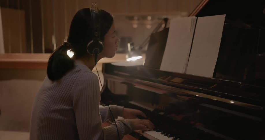 Pianist sits in recording studio and plays piano