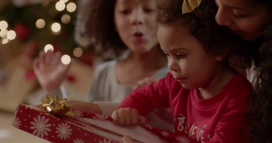 A family opens presents next to a christmas tree