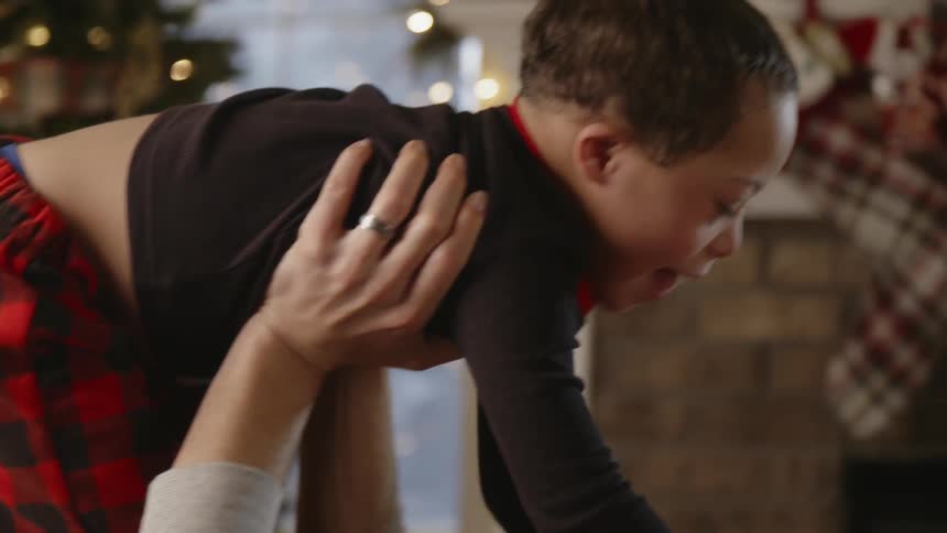 Father lifts son into air near christmas tree
