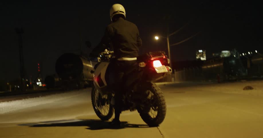 Motorcyclist waits on cycle at night