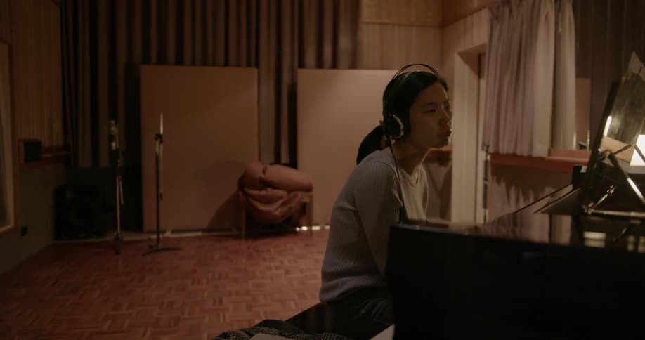 A woman plays piano in a studio