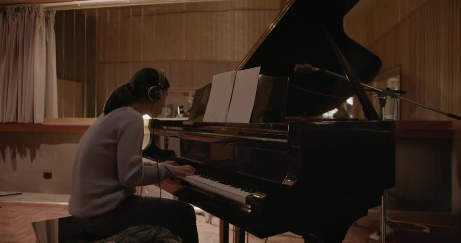 A woman plays piano in a studio
