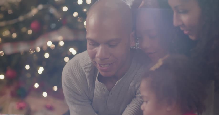 A family reads a book next to a christmas tree