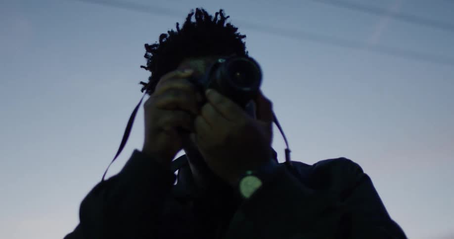 Man takes a photograph outside at dusk