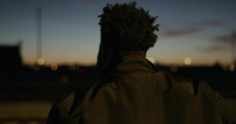 A man is walking outside at dusk