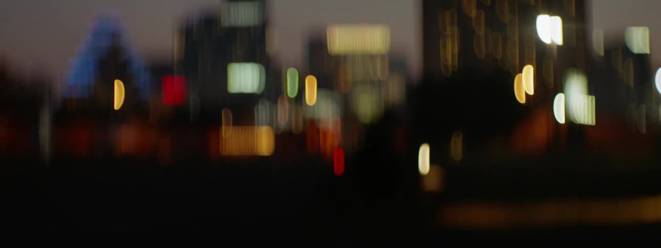 A motorcyclist rides in a city at dusk