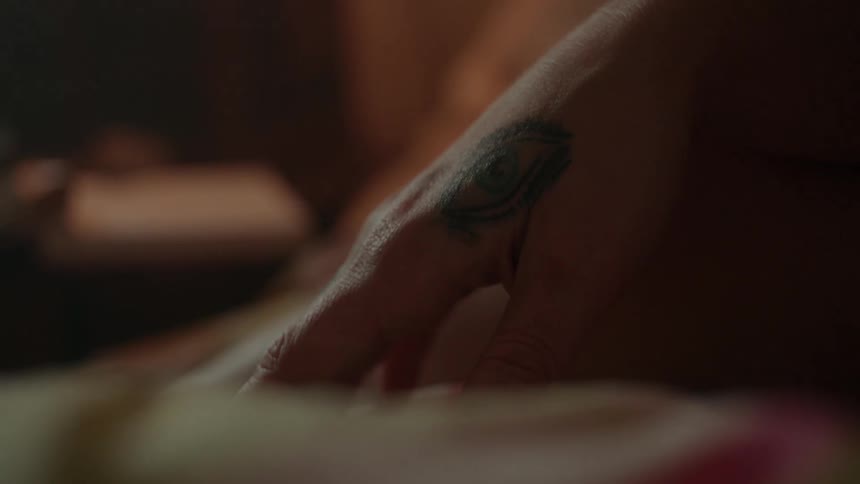 A woman rests her hand on a bed