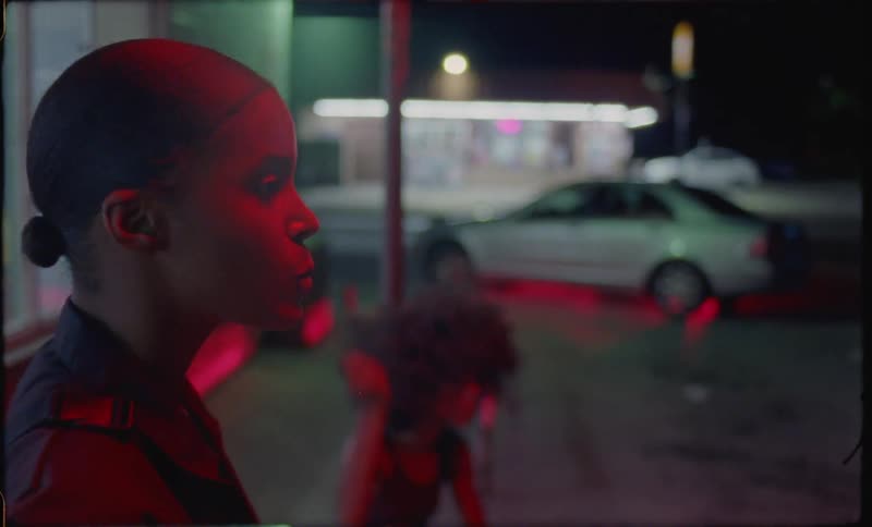 A woman is chewing gum and blowing bubbles outside at night