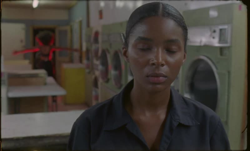 There are 2 women in a laundromat and one of them is stretching